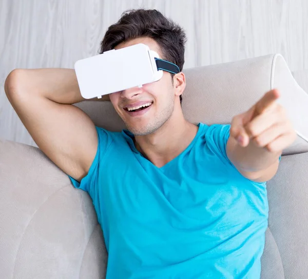 Jovem vestindo óculos VR relaxando no sofá sofá — Fotografia de Stock