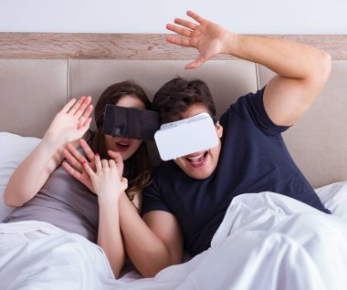 Yatakta sanal gerçeklik gözlüklü eş ve koca.