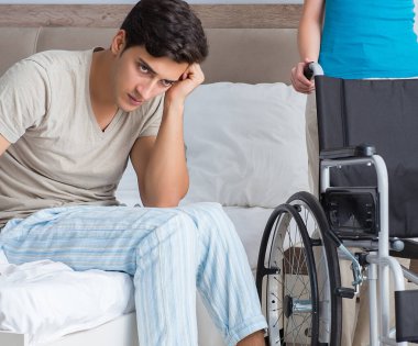 Üzgün karısıyla birlikte tekerlekli sandalyedeki umutsuz adam.