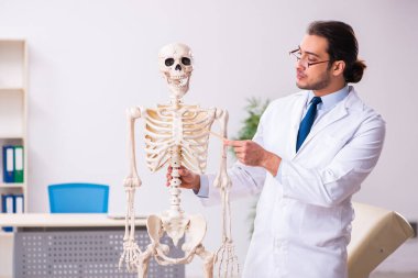 İskeleti olan genç erkek doktor.