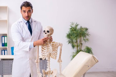 İskeleti olan genç erkek doktor.