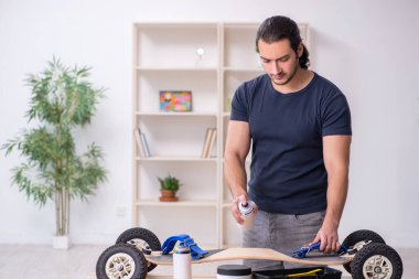 Kaykay tamir eden genç bir erkek tamirci.