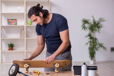 Kaykay tamir eden genç bir erkek tamirci.