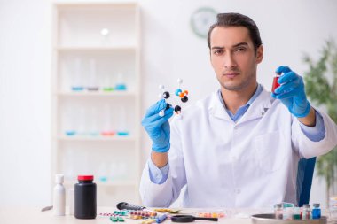 Uyuşturucu sentezi konseptinde genç erkek laboratuvar asistanı