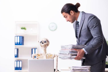 Genç erkek çalışan ve iskelet ofiste.