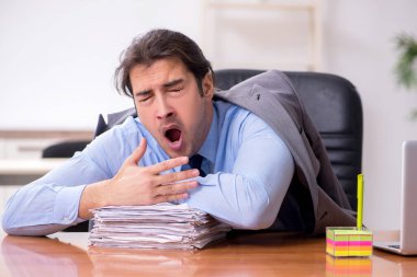 Genç erkek çalışan ofiste uyuyor.