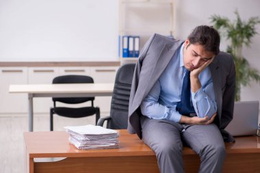 Genç erkek çalışan ofiste uyuyor.