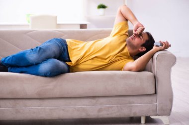 Genç adam evde televizyon izliyor.