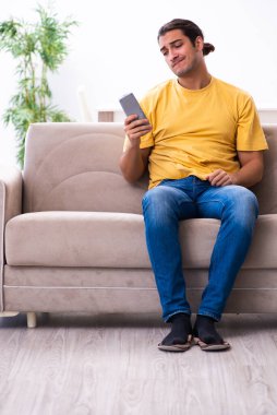 Genç adam evde televizyon izliyor.