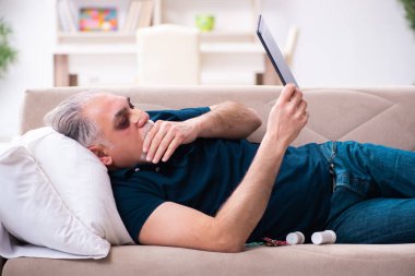 Evde dinlenen yaralı gözlü yaşlı adam.