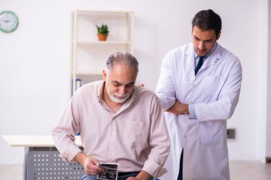 Yaşlı hasta genç erkek doktoru ziyaret ediyor.