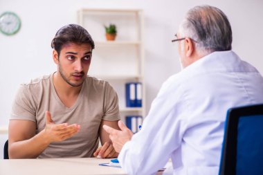 Yaralı genç adam deneyimli erkek doktor travmasını ziyaret ediyor.