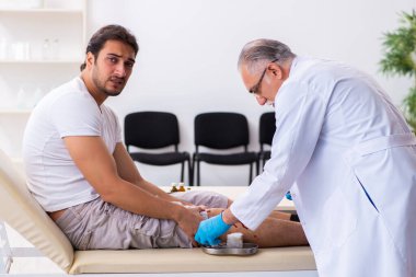 Yaralı adam ilk yardım konseptinde yaşlı doktoru ziyaret ediyor.