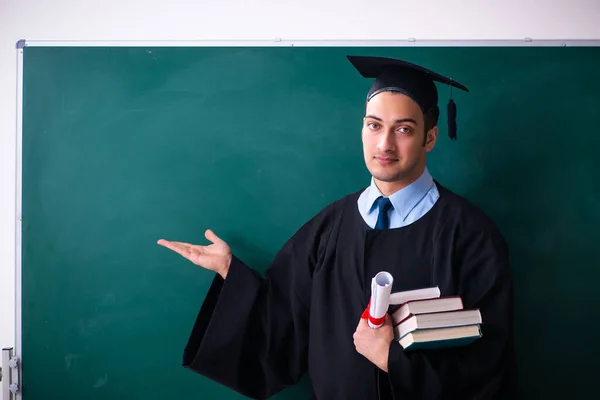 Young male graduate in front of board — Stock Photo, Image