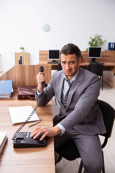 Joven empleado masculino infeliz con el trabajo excesivo — Foto de Stock