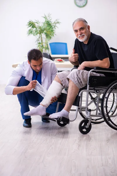 Old injured man visiting young male doctor traumatologist