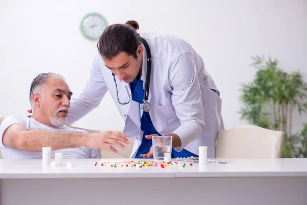 Ung manlig läkare besöker gammal manlig patient hemma — Stockfoto