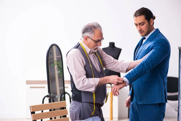 Joven hombre de negocios visitando viejo sastre masculino —  Fotos de Stock