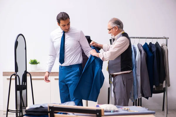 Jovem empresário visitando velho alfaiate masculino — Fotografia de Stock