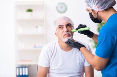 Yaşlı adam estetik ameliyat için erkek doktoru ziyaret ediyor.