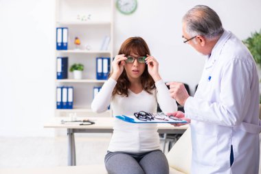 Genç kadın yaşlı erkek doktor göz doktorunu ziyaret ediyor.
