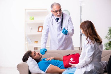 İki doktor hasta bir genci ziyaret ediyor.