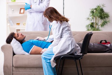 İki doktor hasta bir genci ziyaret ediyor.