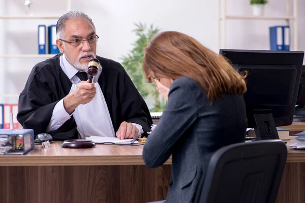 Oude mannelijke rechter en vrouwelijke cliënt in het kantoor — Stockfoto