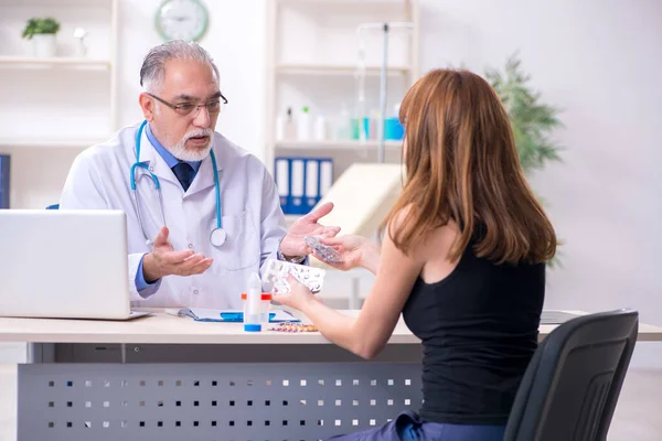 Jovem mulher visitando velho médico masculino — Fotografia de Stock