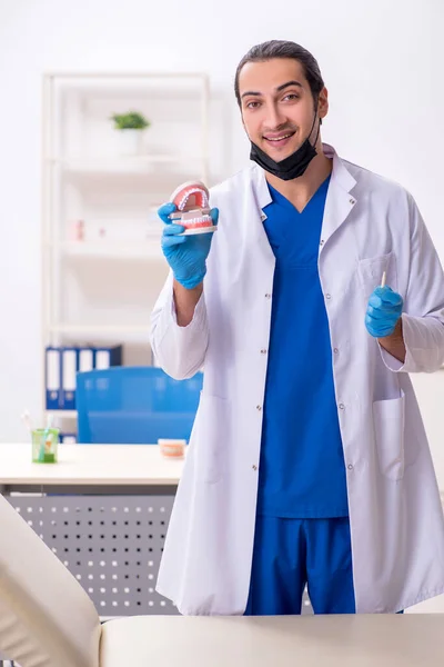 Jonge mannelijke tandarts werkzaam in de kliniek — Stockfoto