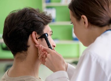 Tıbbi muayene sırasında kadın doktor hastaların kulaklarını kontrol ediyor.