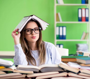 Sınavlara bir sürü kitapla hazırlanan genç kız öğrenci.