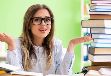 Sınavlara bir sürü kitapla hazırlanan genç kız öğrenci.