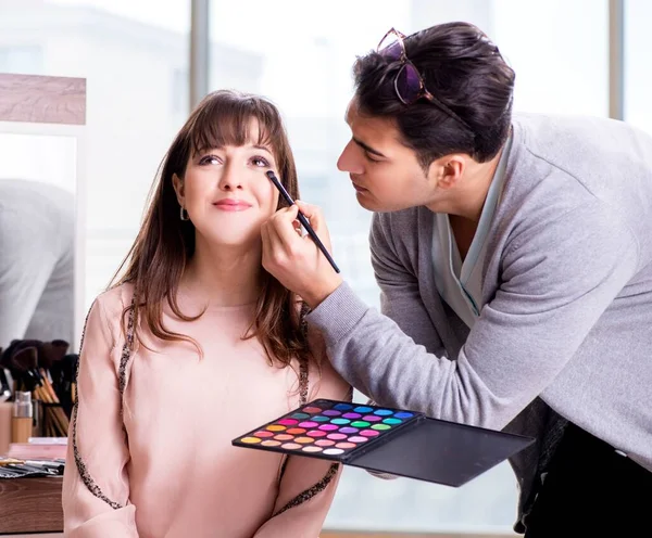 Muž dělá make-up pro roztomilé ženy v salonu krásy — Stock fotografie