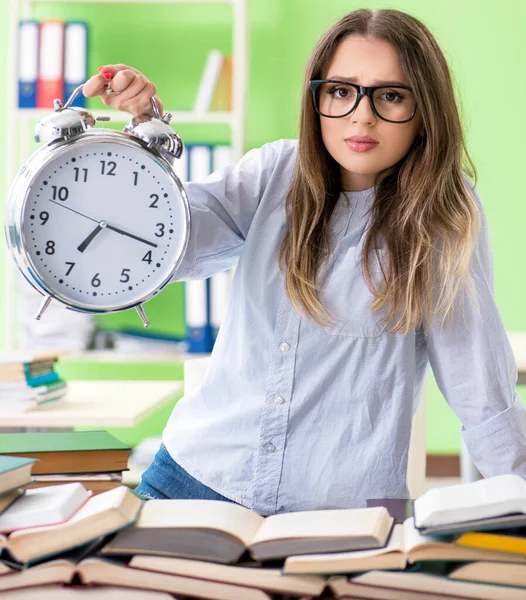 Jonge vrouwelijke student bereidt zich voor op examens met veel boeken in de tijd — Stockfoto