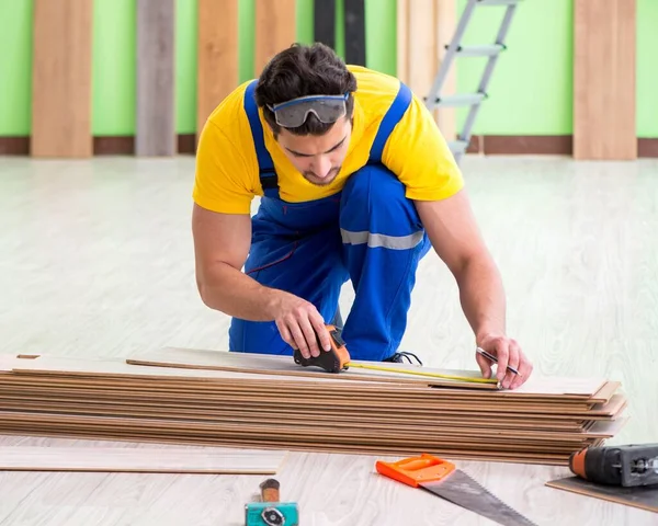 Empreiteiro profissional que coloca piso em casa — Fotografia de Stock