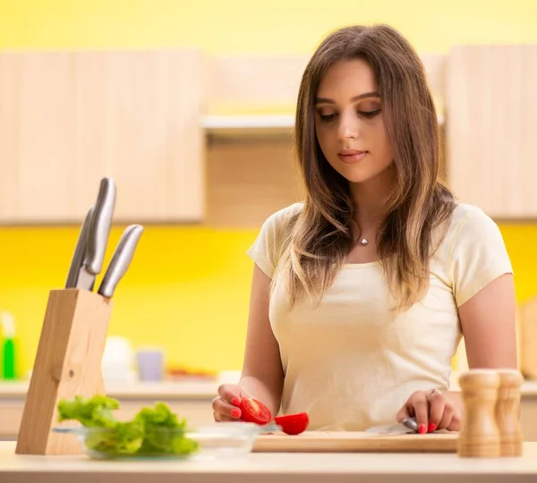Mujer joven preparando ensalada en casa en la cocina — Foto de Stock