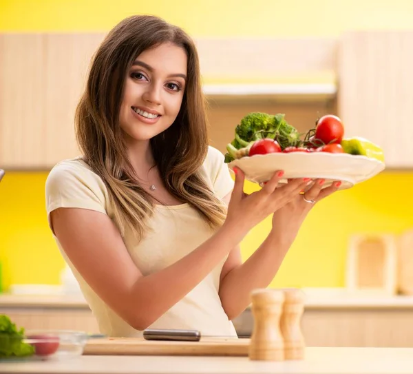 Young woman preparing salad at home in kitchen — Stock Photo, Image