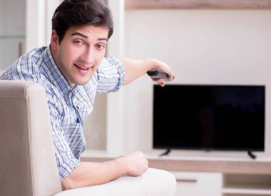 Genç adam evde televizyon izliyor.