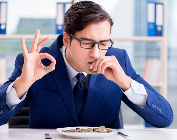 Funny businessman eating gold coins in office