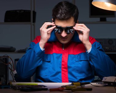 Bilgisayar uzmanı gece geç saatlerde bilgisayarı tamir ediyor.