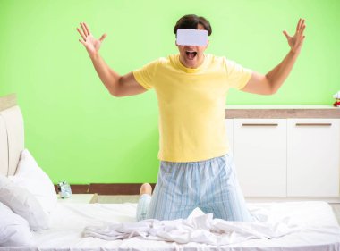 Yatak odasında sanal gözlüklü genç adam.