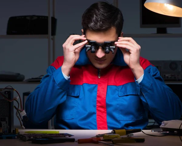 Bilgisayar uzmanı gece geç saatlerde bilgisayarı tamir ediyor.