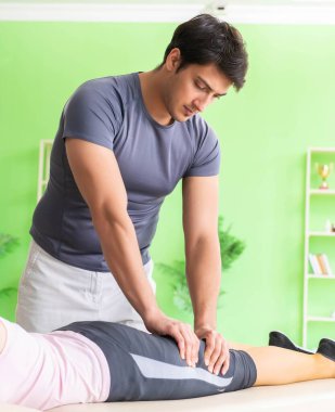 Genç doktor masör hastaya masaj yapıyor.