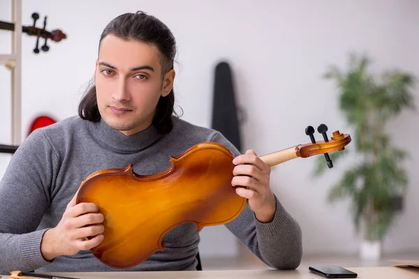 Young male repairman repairing violin