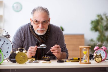 Atölyede çalışan yaşlı bir erkek saatçi.