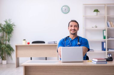 Klinikte çalışan genç erkek doktor.