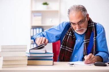 Yaşlı erkek yazar tüyle kitap yazıyor.