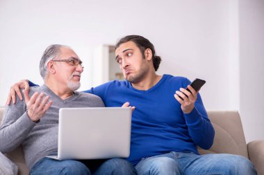 Baba oğul kanepede bilgisayar başında oturuyor.