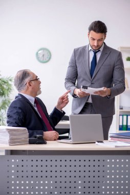 Eski patron ve genç asistanı ofiste çalışıyor.